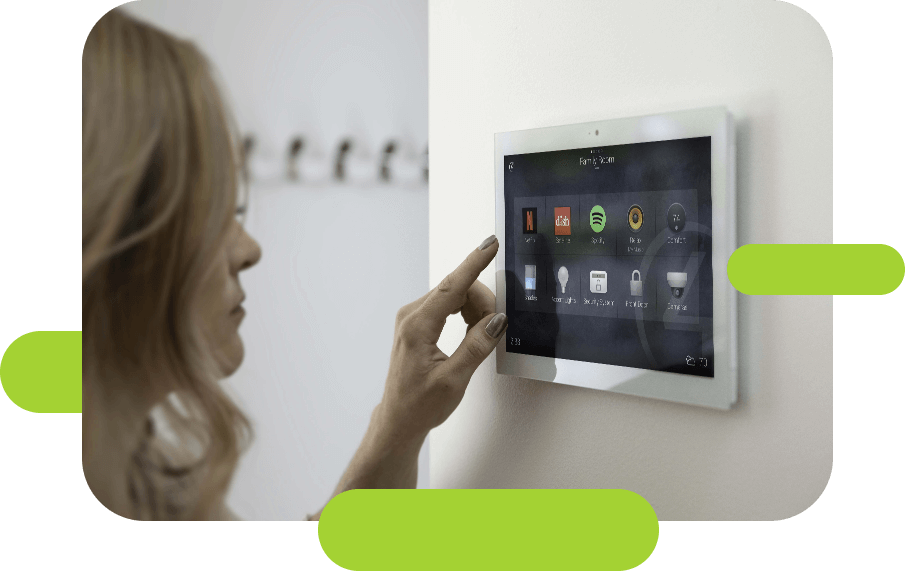 woman points to tablet on wall that is connected to temperature, sound, and more