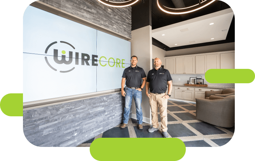 two Wirecore employees stand next to big screen with Wirecore logo