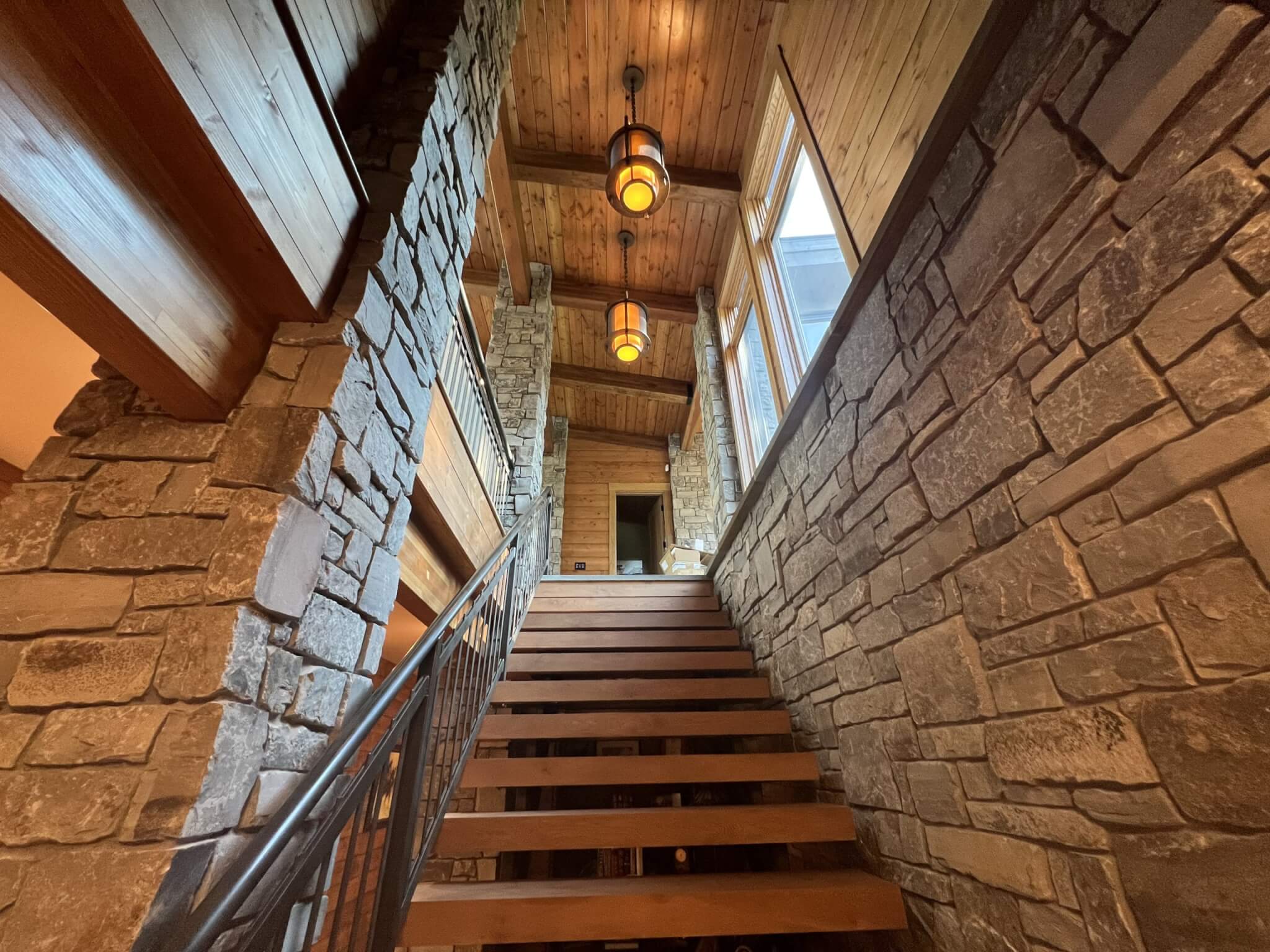 two hanging ceiling lights turned on, down stone hall with stairs facing up